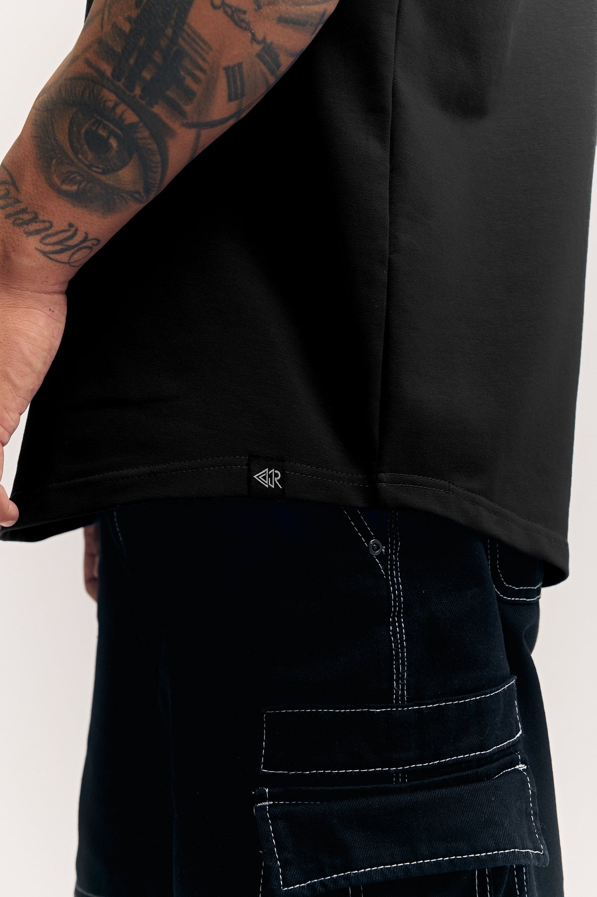 Black Eternal relaxed fit polo t-shirt for men, hem and woven label close-up – Rewind Apparel Dubai