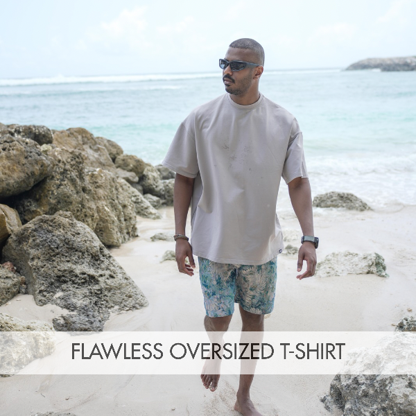 Man wearing a flawless oversized blue t-shirt at the beach, styled for a relaxed, casual look.