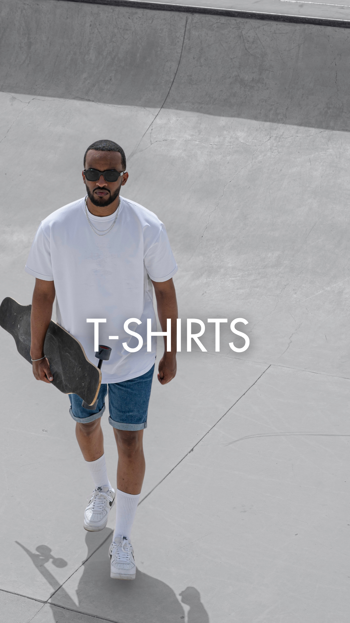 Man in a white Eternal relaxed fit t-shirt holding a skateboard – men's t-shirts by Rewind Apparel Dubai