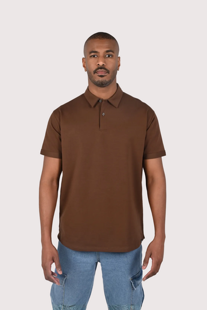 Man wearing a brown polo shirt and blue jeans on a white background